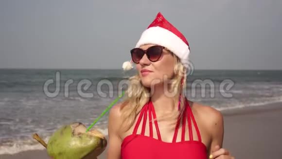 穿着圣诞帽在海滩上美丽的年轻女子视频的预览图