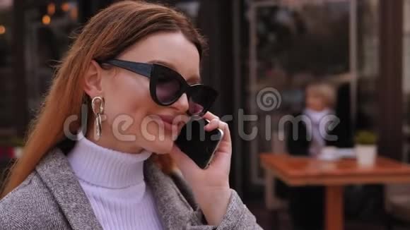 城市里一个戴着墨镜手里拿着手机的女孩的脸视频的预览图