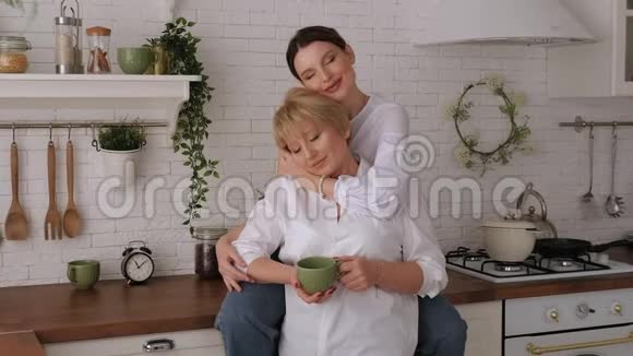 一幅幸福的老母亲和女儿在厨房里的画像他们喝茶视频的预览图