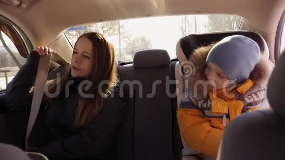 一个女人坐在车里系安全带孩子坐在她旁边视频的预览图