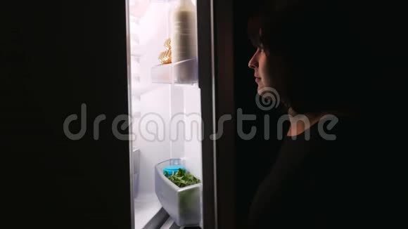 一个饥饿的女孩在晚上打开冰箱拿蛋糕视频的预览图