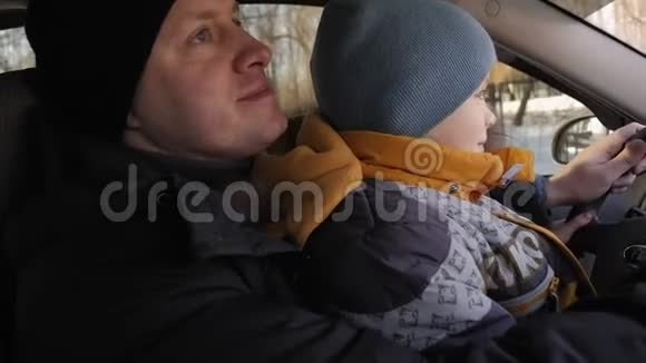 一个好奇的男孩和他父亲在冬天开车的特写肖像视频的预览图