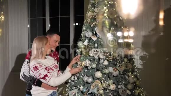 幸福的一对穿着针织毛衣在家里装饰圣诞树的夫妇视频的预览图