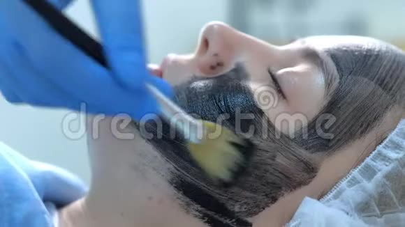美容师用刷子侧视将碳纳米凝胶涂于女性面部皮肤视频的预览图
