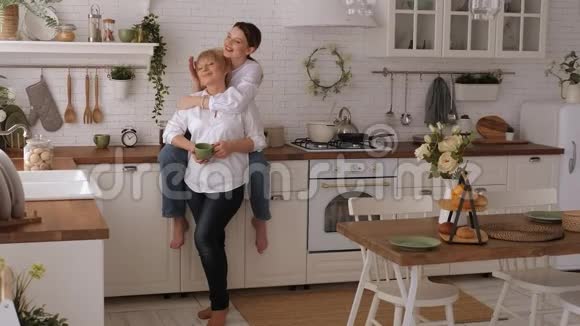 一幅幸福的老母亲和女儿在厨房里的画像他们喝茶视频的预览图