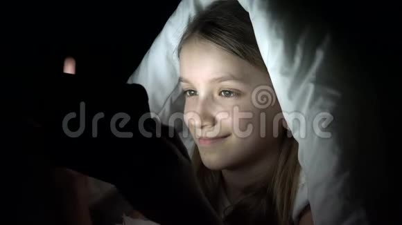 儿童在黑暗中玩平板电脑少女在床上浏览互联网儿童不睡觉视频的预览图