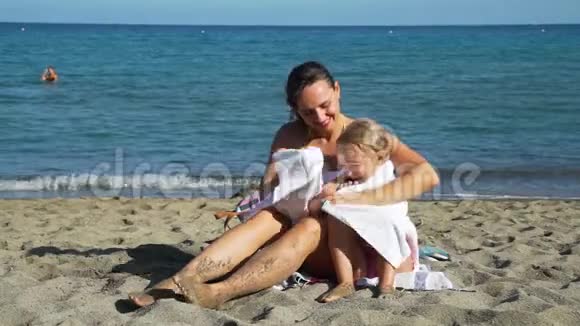 妈妈在海滩上用毛巾给女儿盖被子视频的预览图