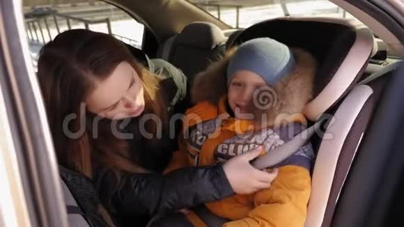 冬天一位母亲用汽车安全带系住儿子视频的预览图