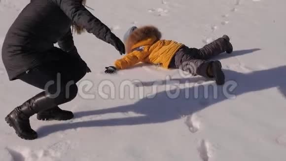一家人躺在雪地里做雪天使母亲和孩子躺在雪地上视频的预览图