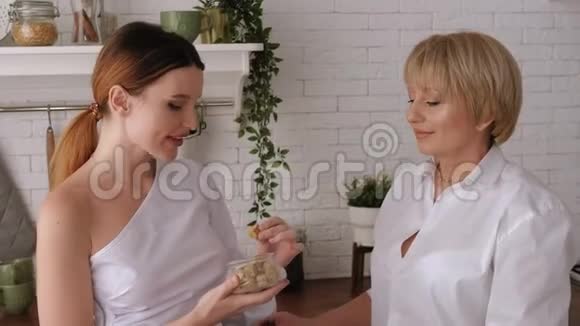 年迈的母亲和一个成年的女儿在厨房里手里拿着糖果视频的预览图