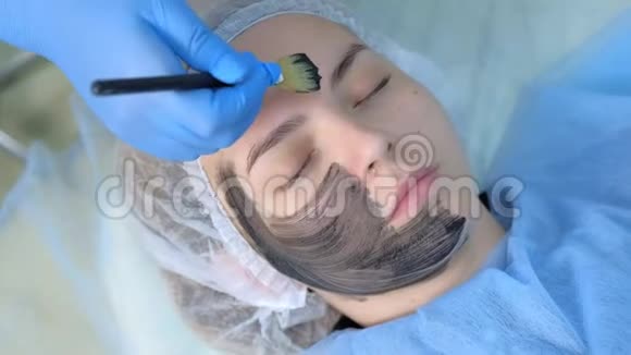 美容师用刷子将碳纳米凝胶涂于女性面部皮肤上视频的预览图