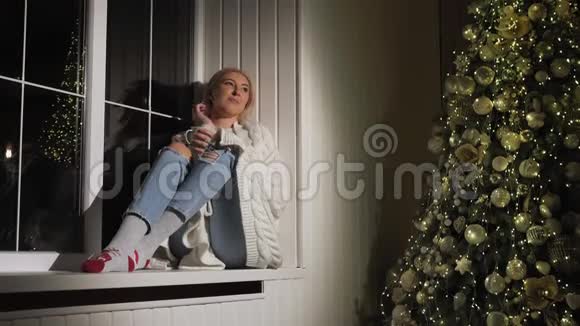 穿着毛衣窗台上放着一杯热茶的女孩圣诞画像视频的预览图