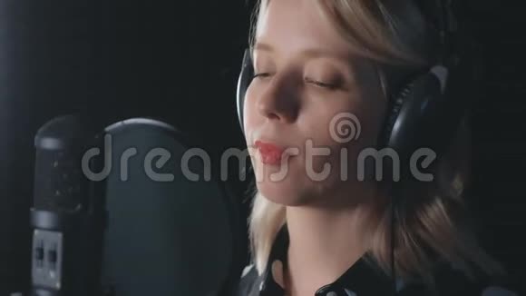 女歌手戴耳机演唱麦克风录音歌曲的肖像视频的预览图