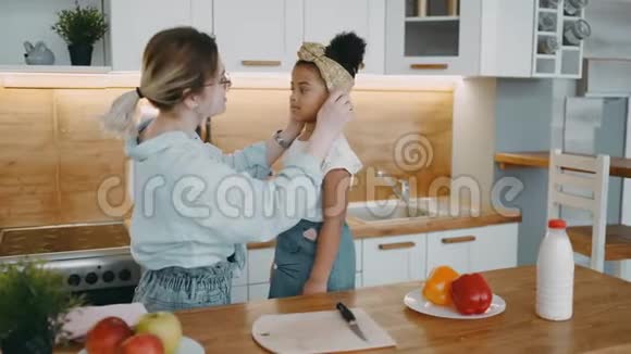 细心的妈妈妈妈戴着眼镜为孩子女儿纠正头发绷带非裔美国人的孩子开始做饭视频的预览图