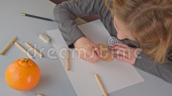 可爱的金发小女孩用彩色铅笔画成熟的橙色视频的预览图