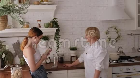 一位老母亲和一位成年女儿在现代厨房一起准备午餐视频的预览图
