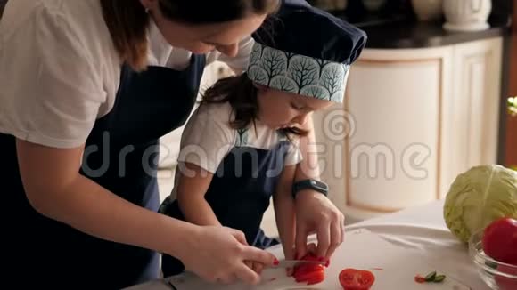 一个母亲和一个小女儿一起切番茄的特写镜头视频的预览图