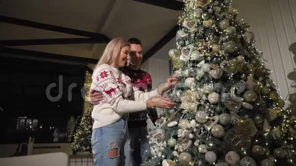 恋爱中的年轻夫妇在家里装饰一棵圣诞树视频的预览图