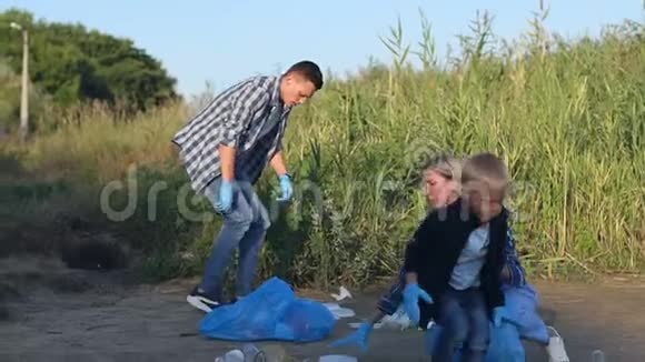 一个戴手套的小男孩帮助志愿者在公园里收集塑料垃圾视频的预览图