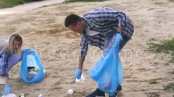 特写一男一女在河边的沙滩上收集垃圾视频的预览图