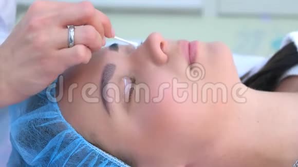 美容师用麻醉药在眼睑上涂霜给女性侧视视频的预览图