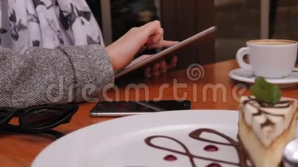 一个女孩在咖啡馆里用平板电脑和卡布奇诺双手特写视频的预览图