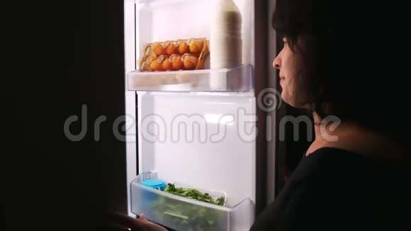 女人在夜里打开冰箱拿蛋糕关上冰箱视频的预览图