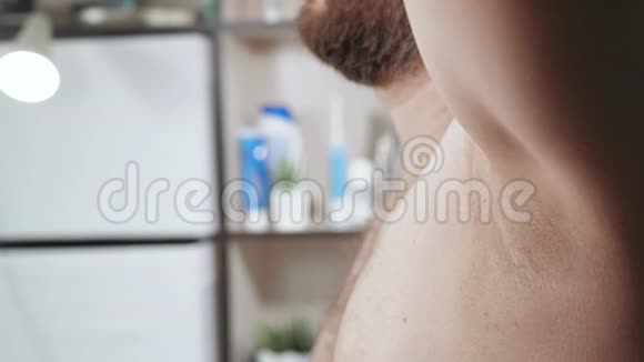 刮胡子的概念留着胡子的白种人正在浴室里用泡沫刮掉他的左腋窝侧视关闭视频的预览图