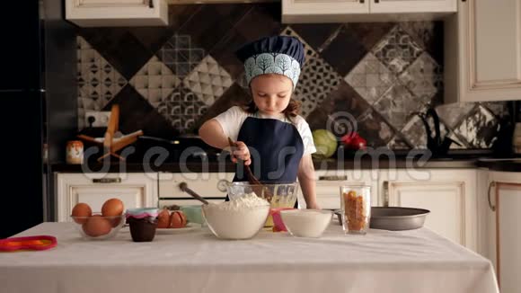 一个小女孩在厨房里用一个木勺她准备面团视频的预览图