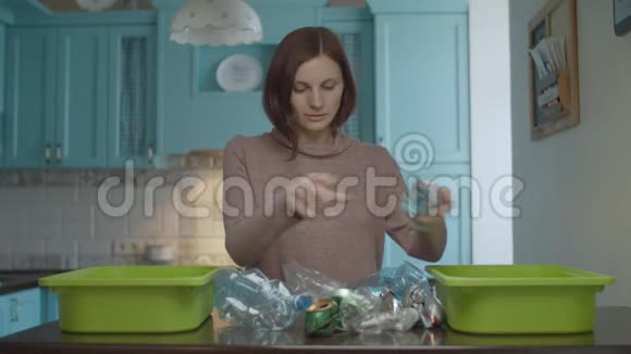 年轻的30多岁的黑发女人把家里的垃圾分类回收塑料和锡环保家庭减少塑料视频的预览图