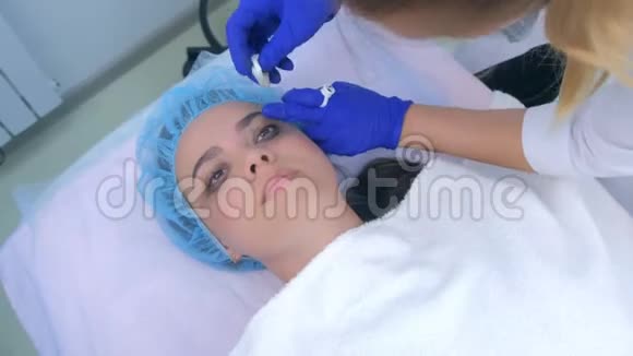 美容师从女性眼区擦拭油漆制作永久眼线视频的预览图