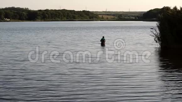 渔夫拿着鱼竿站在水里河湾的渔夫视频的预览图