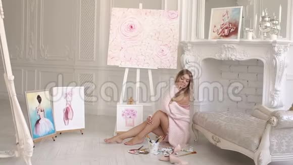穿着粉红色毛衣的女画家坐在卧室里画中有调色板视频的预览图