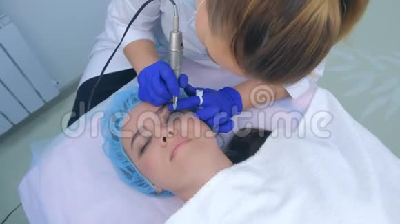 美容师在美容诊所为女性眼睑做永久性眼线化妆视频的预览图