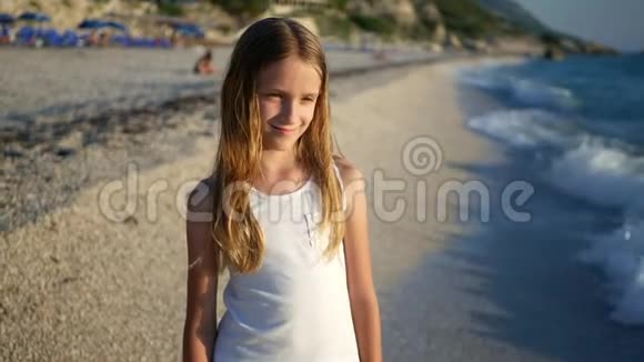 日落时在海滩上玩耍的孩子看海浪的孩子岸上的女孩肖像视频的预览图