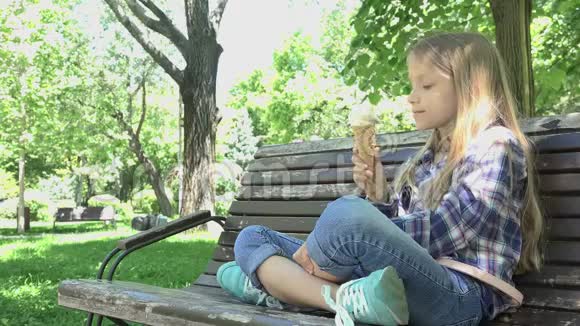 儿童在公园吃冰淇淋儿童在游乐场坐在长凳上放松视频的预览图
