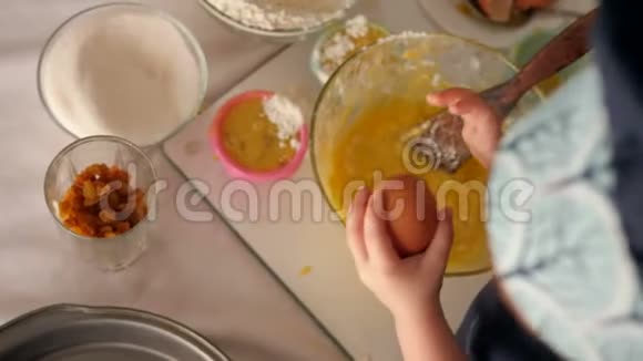 一个三岁的小女孩把鸡蛋打碎成一盘面团视频的预览图