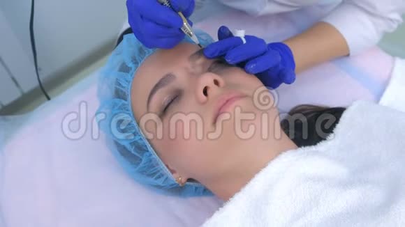 美容师在手套做永久眼线化妆给女人面部特写视频的预览图
