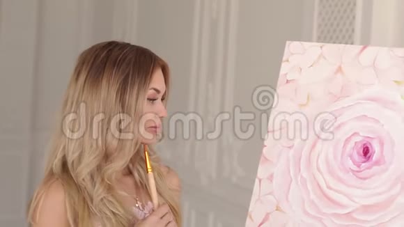 一位穿毛衣的女艺术家正在画室欣赏她的画视频的预览图