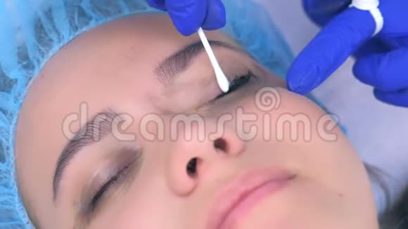 美容师从女性眼睑上擦拭油漆制作永久眼线视频的预览图