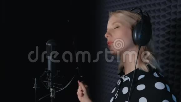 女歌手戴耳机唱歌麦克风录音歌曲在录音室视频的预览图