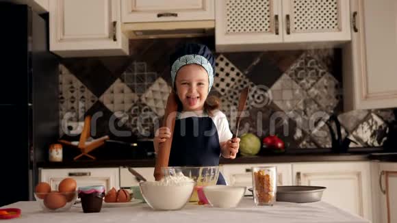 一个可爱的小笑女手里拿着擀面杖在厨房里视频的预览图