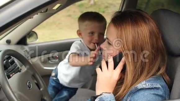 一个淘气的孩子沉迷于汽车他阻止他的母亲打电话视频的预览图