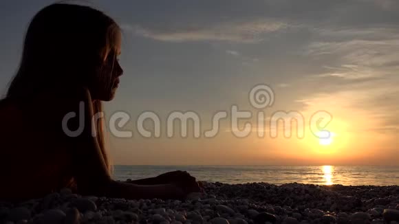 海滩上的孩子日落时在海滩上玩耍的孩子看着女孩在学习卵石视频的预览图
