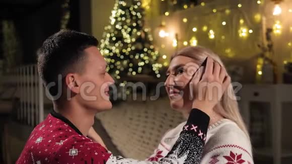 一个男人的特写镜头轻轻地抚摸着他女朋友的头靠近圣诞树视频的预览图