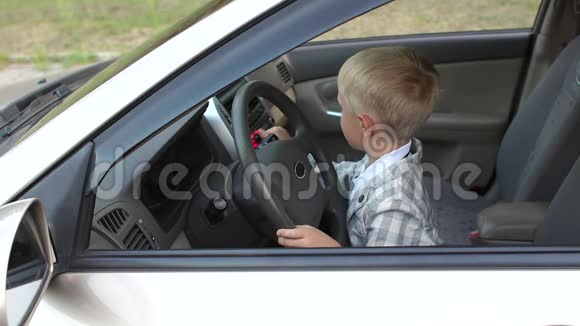 一个小男孩坐在汽车的车轮后面他使音乐更响亮跳舞视频的预览图
