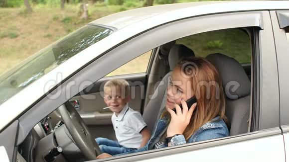 一个孩子坐在前排坐在车里妈妈在打电话视频的预览图
