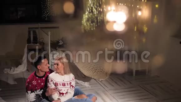 年轻幸福的一对夫妇正坐在圣诞树附近卧室的地板上视频的预览图