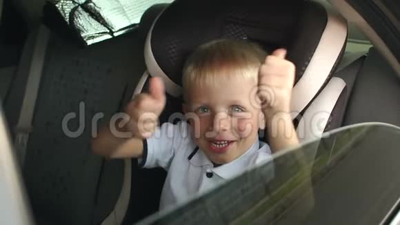 一个快乐的小男孩坐在棕色的儿童汽车座椅上竖起大拇指视频的预览图