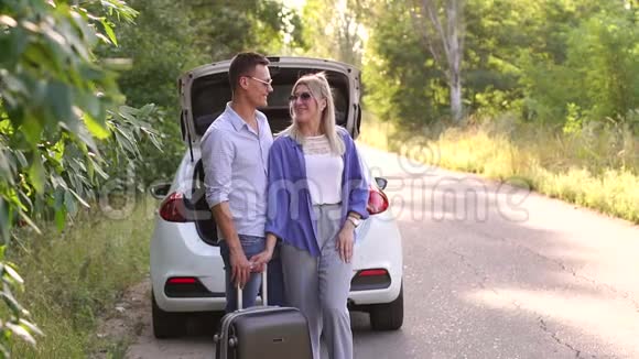 幸福的一对夫妇靠近汽车后备箱户外有手提箱假期旅行视频的预览图